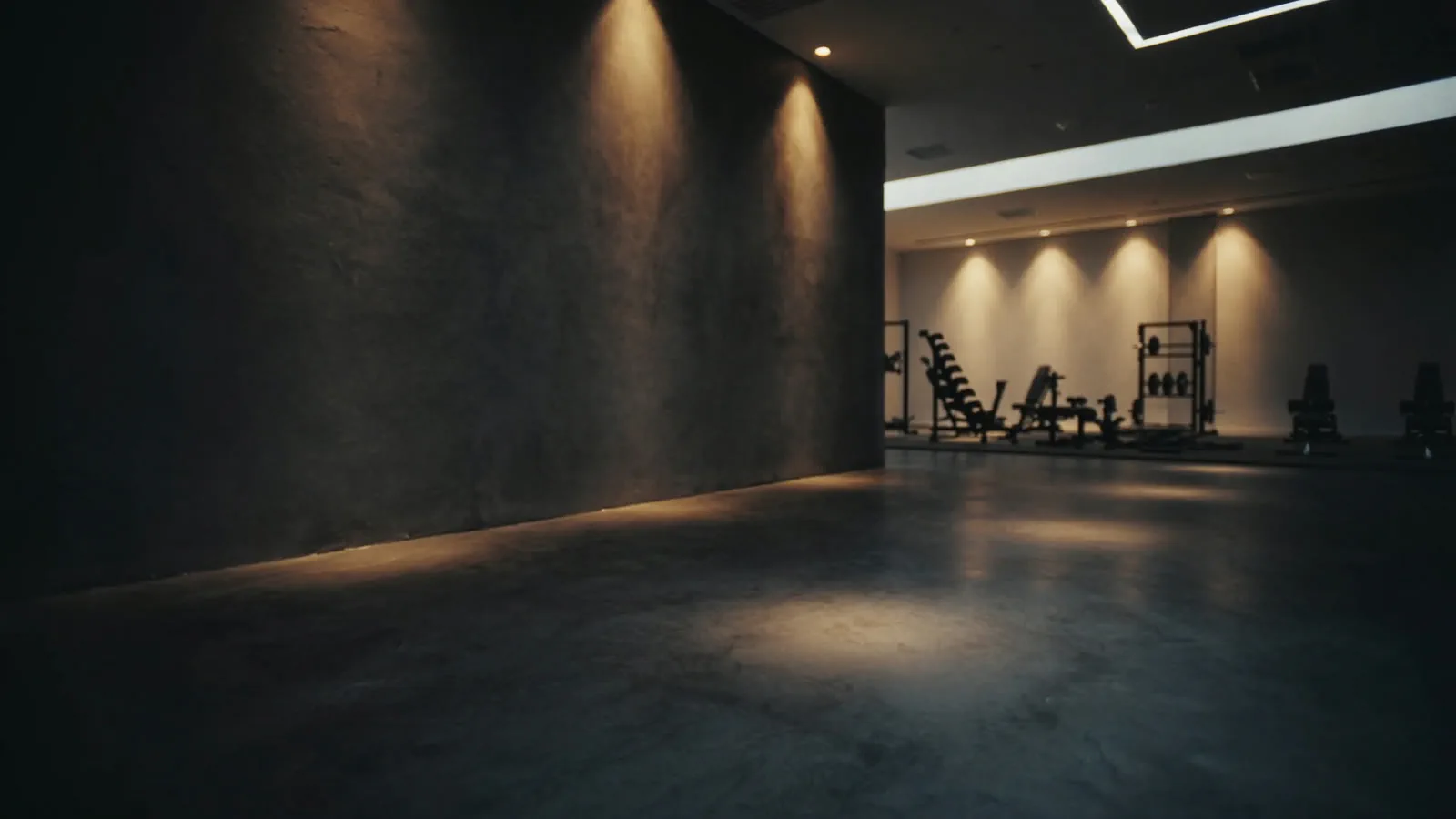 An empty corner of a gym at night, warm light spilling across the floor